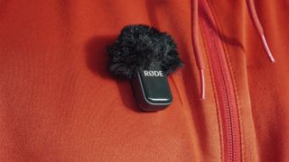 Rode Wireless Micro transmitter attached to a bright orange jacket